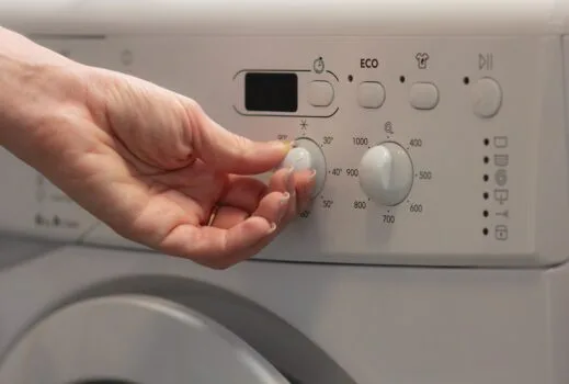 女性轉動洗衣機溫度旋鈕 / Woman switching the temperature on a washing machine