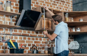 戴眼鏡的男士使用捲尺測量抽油煙機尺寸 / Man in glasses measuring a kitchen range hood with a tape measure