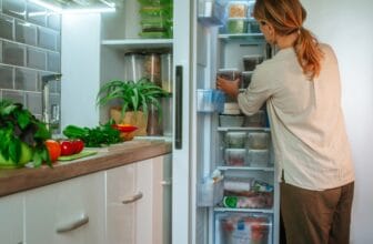 年輕女性從小型冰箱冷凍庫取出食物 / Young woman taking food out of compact fridge freezer